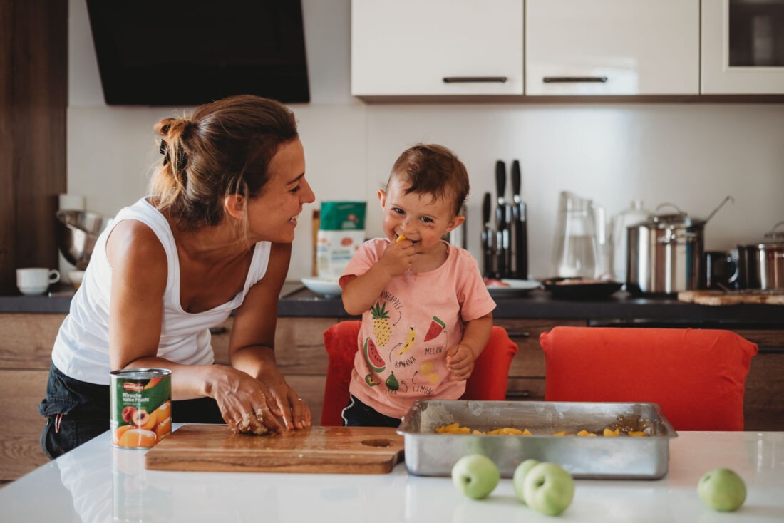 Mother and toddler baking together in the kitchen, sharing laughter during a family lifestyle photo session.