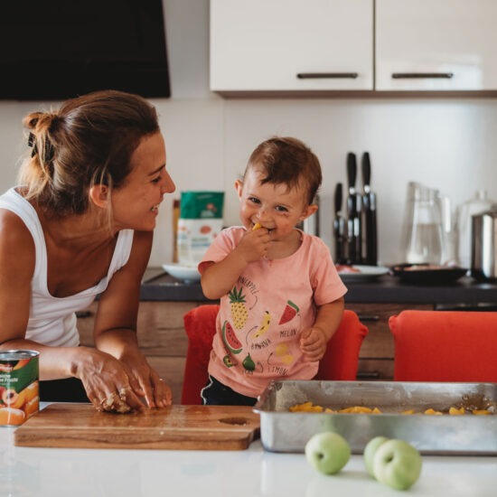 Mother and toddler baking together in the kitchen, sharing laughter during a family lifestyle photo session.