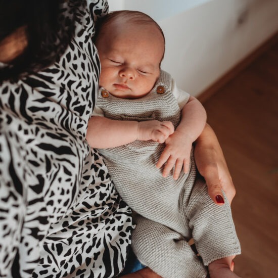 Newborn baby sleeping peacefully in mother’s arms.