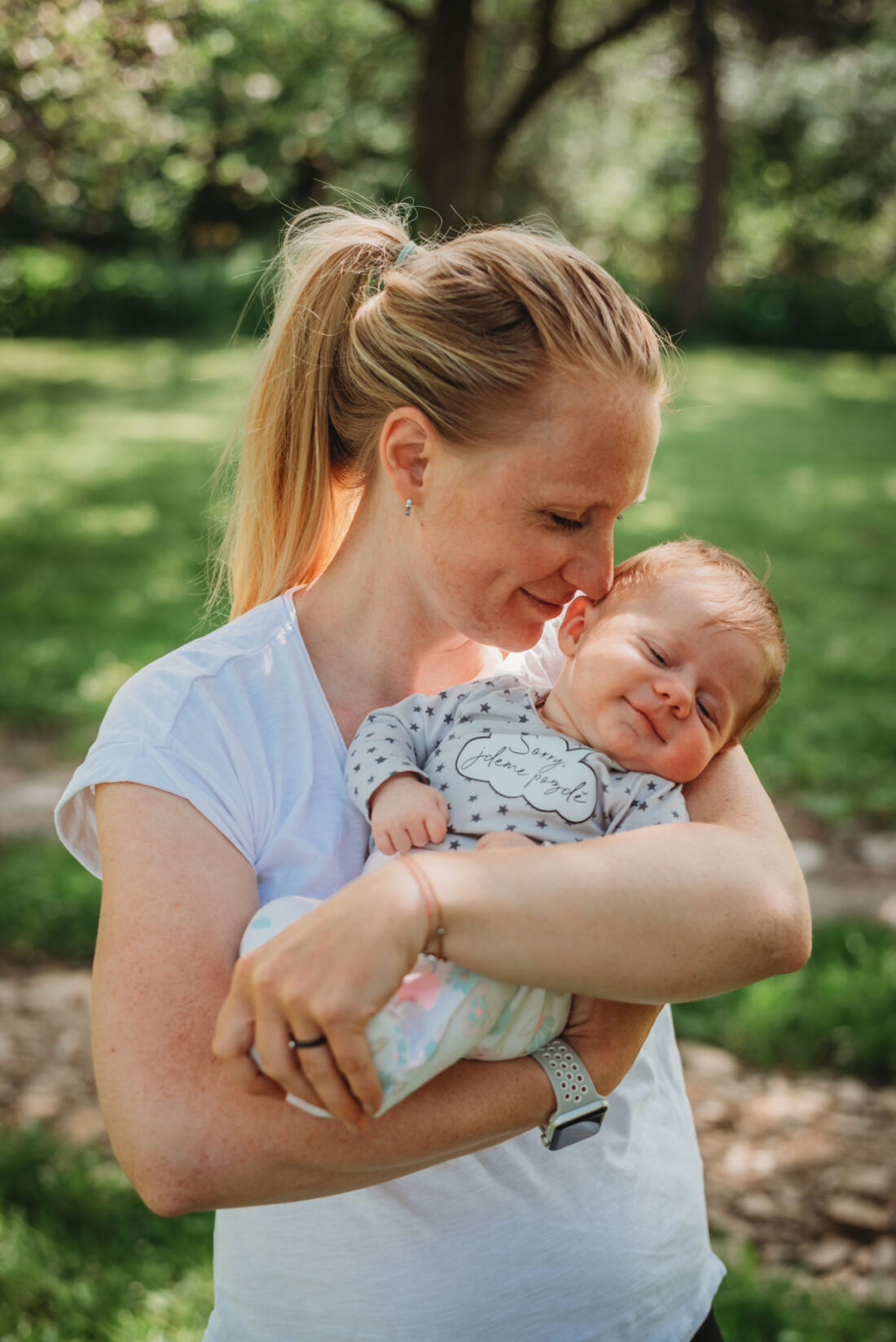 Mom gently smells her baby’s hair during an outdoor baby photo shoot.