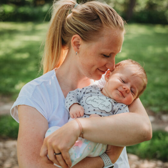Mom gently smells her baby’s hair during an outdoor baby photo shoot.