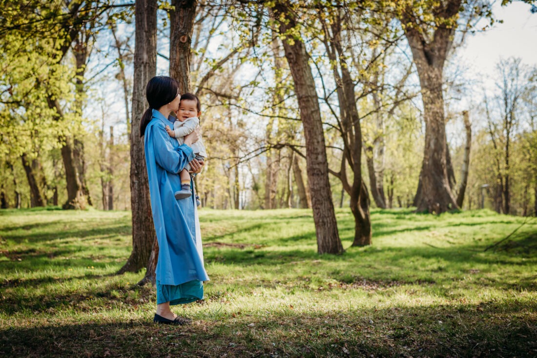 Japanese expat mom hugging her baby in Vienna spring woods.