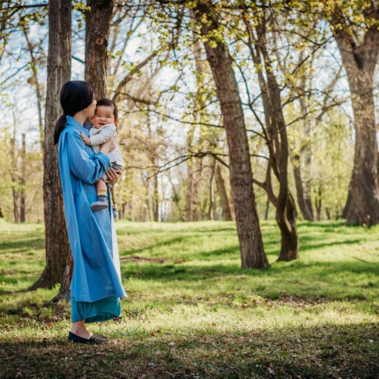 Japanese expat mom hugging her baby in Vienna spring woods.
