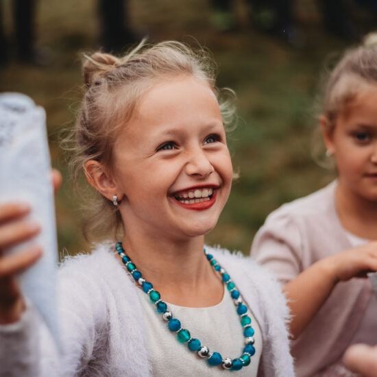 Young flower girl excitedly holding a cone of petals, ready to toss them in celebration.