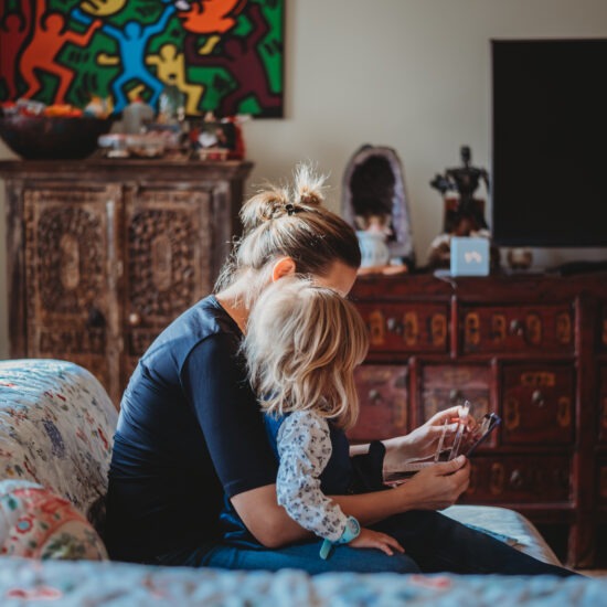 Mother and daughter reading together during cozy in-home family photo session in Vienna.