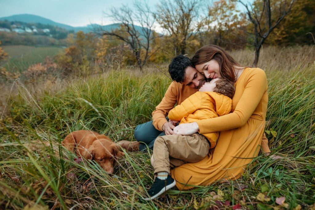 Family cuddling with toddler and dog during autumn photo shoot at Nussberg Vienna