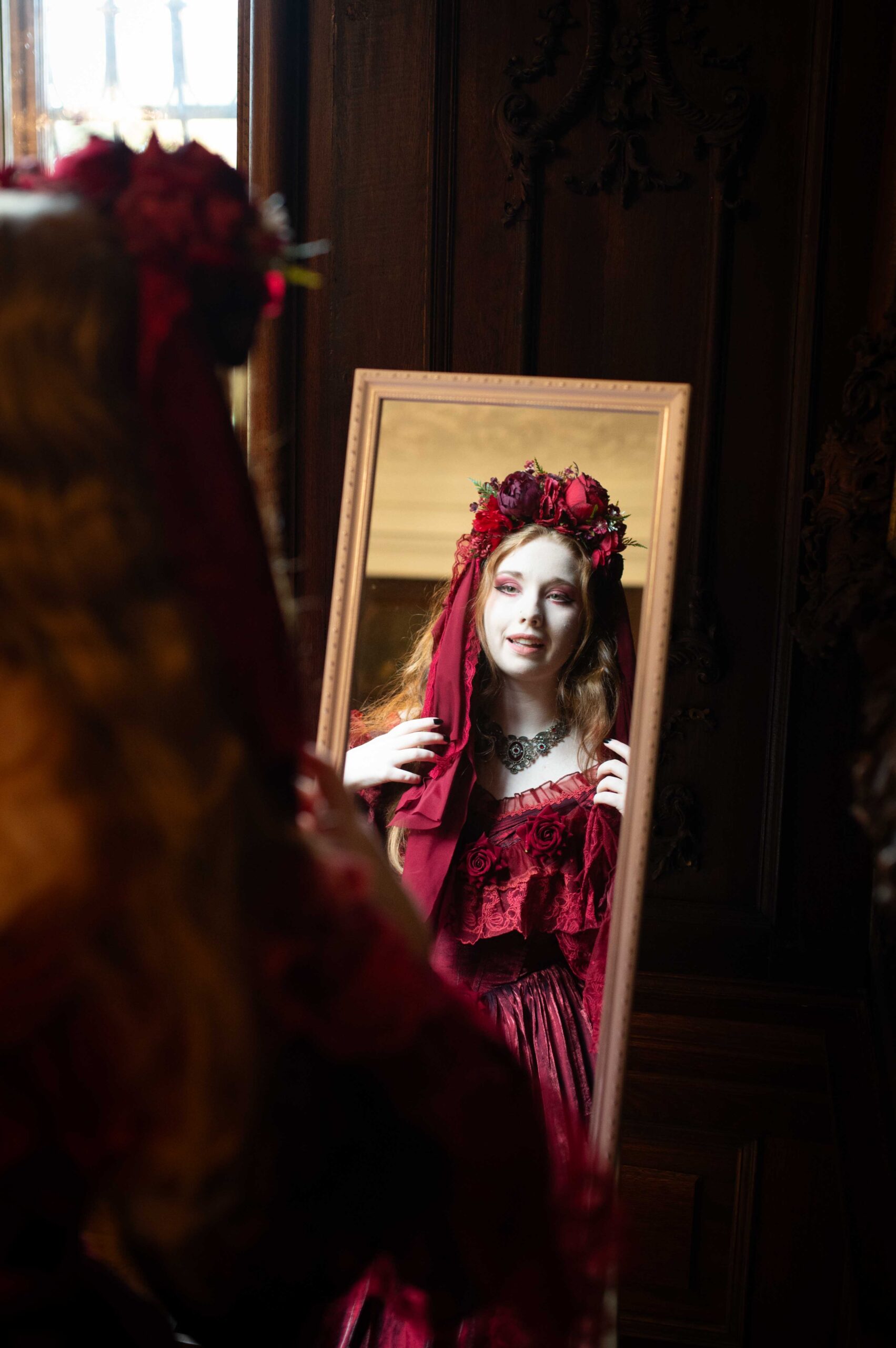 Woman in red baroque dress looking into mirror during LGBTQ wedding at Eckartsau Castle