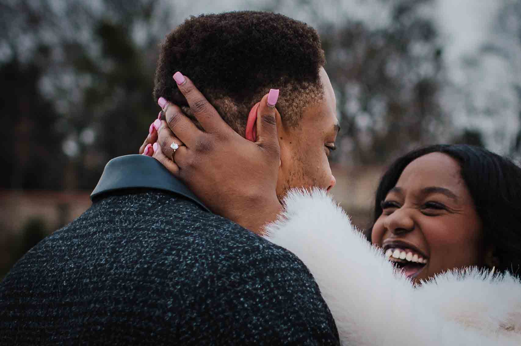 Close-up of an engaged couple embracing, with the engagement ring visible after a proposal