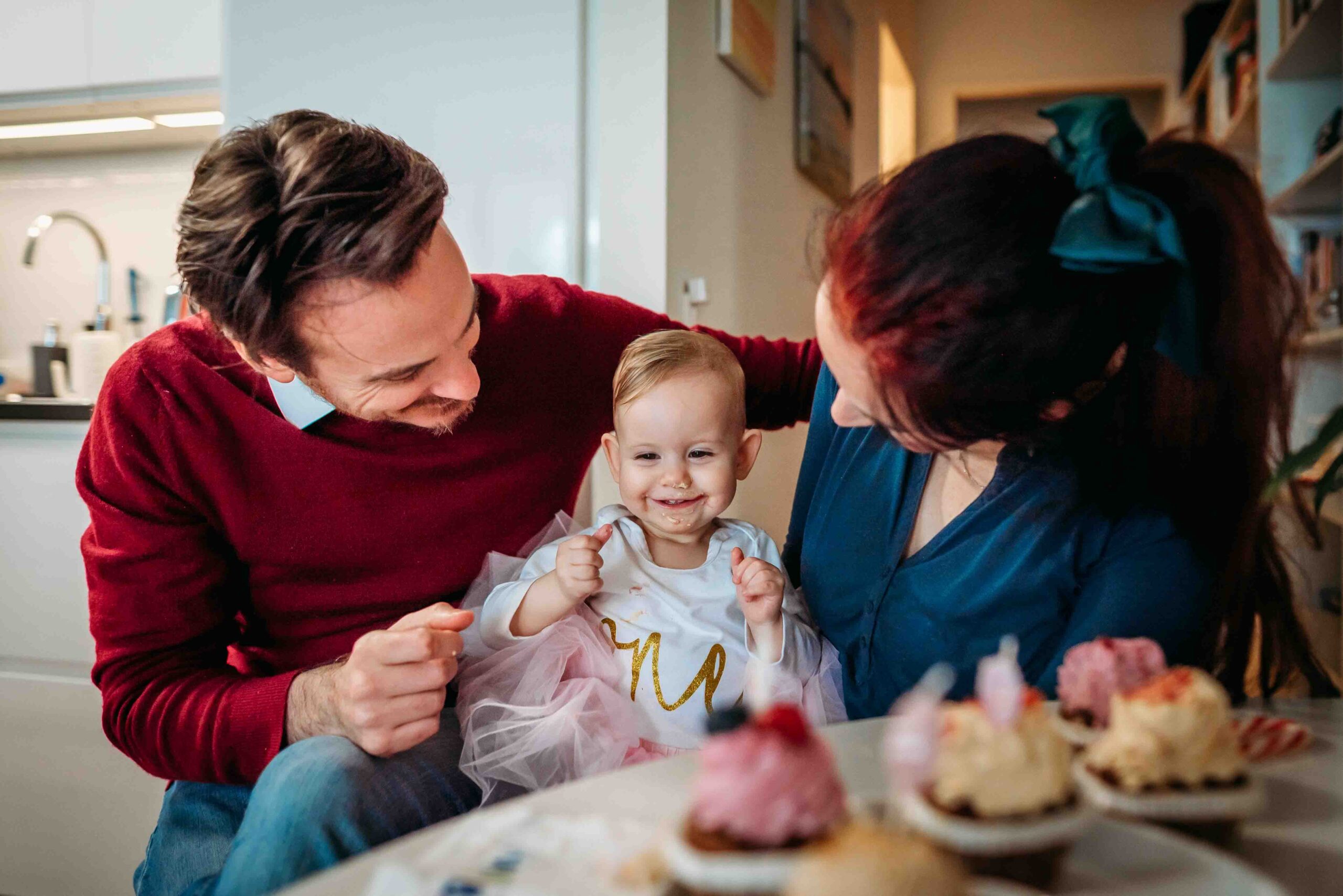 Toddler smiling with parents during first birthday celebration in Vienna