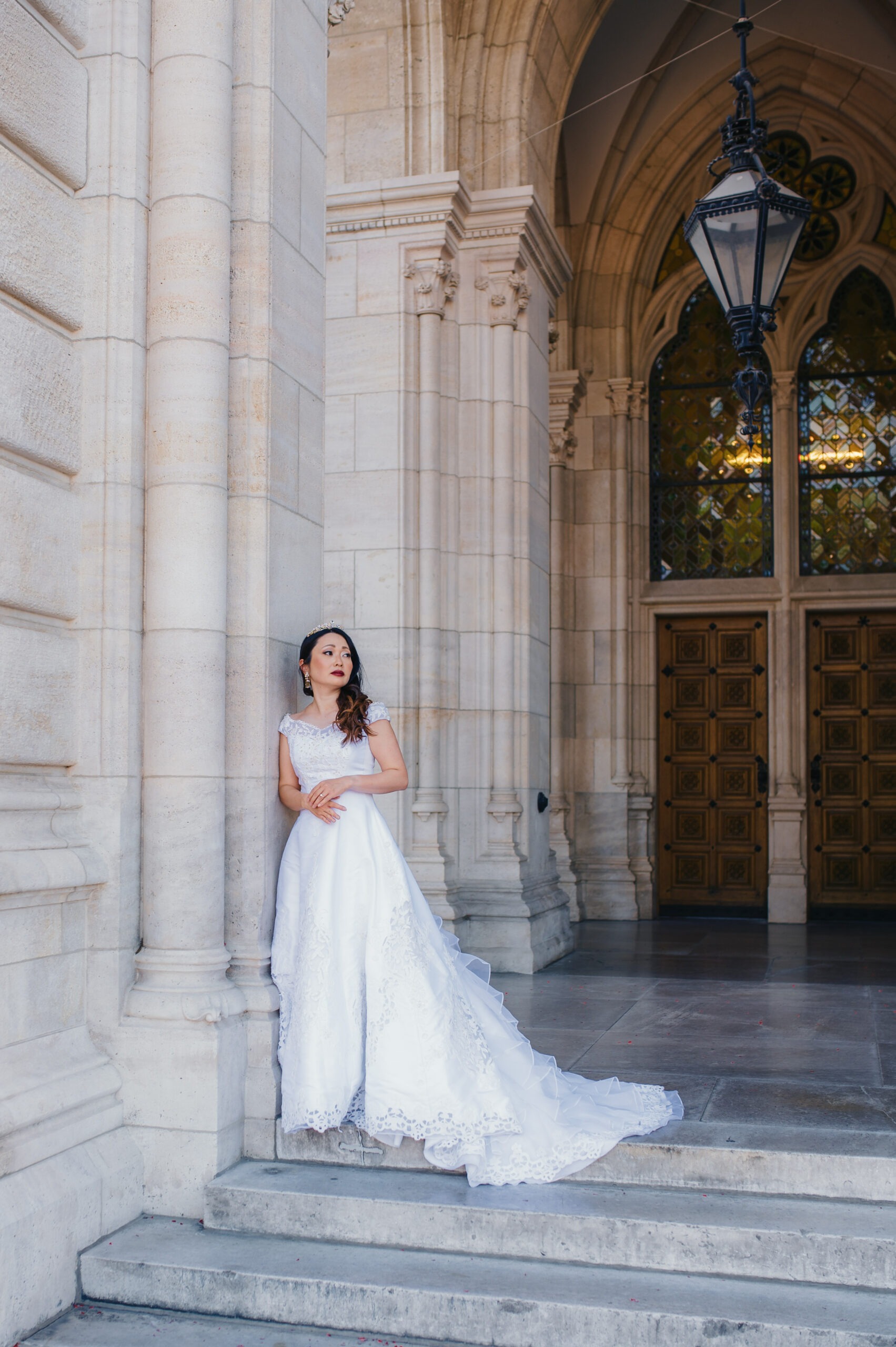 Bride in wedding dress posing beneath historic arches at Vienna Rathaus