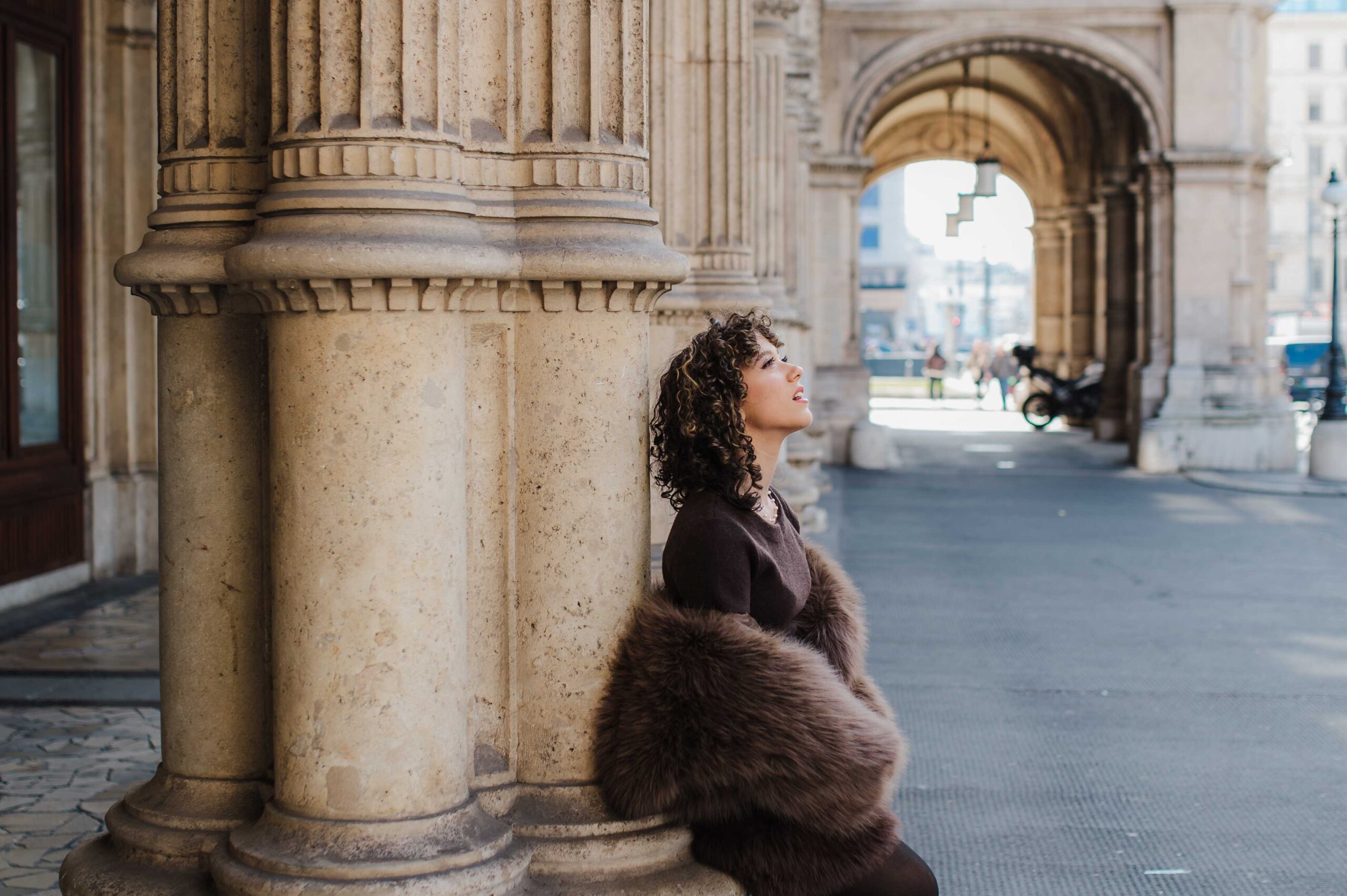 Elegant teenage girl portrait by historic columns of Viennese State Opera