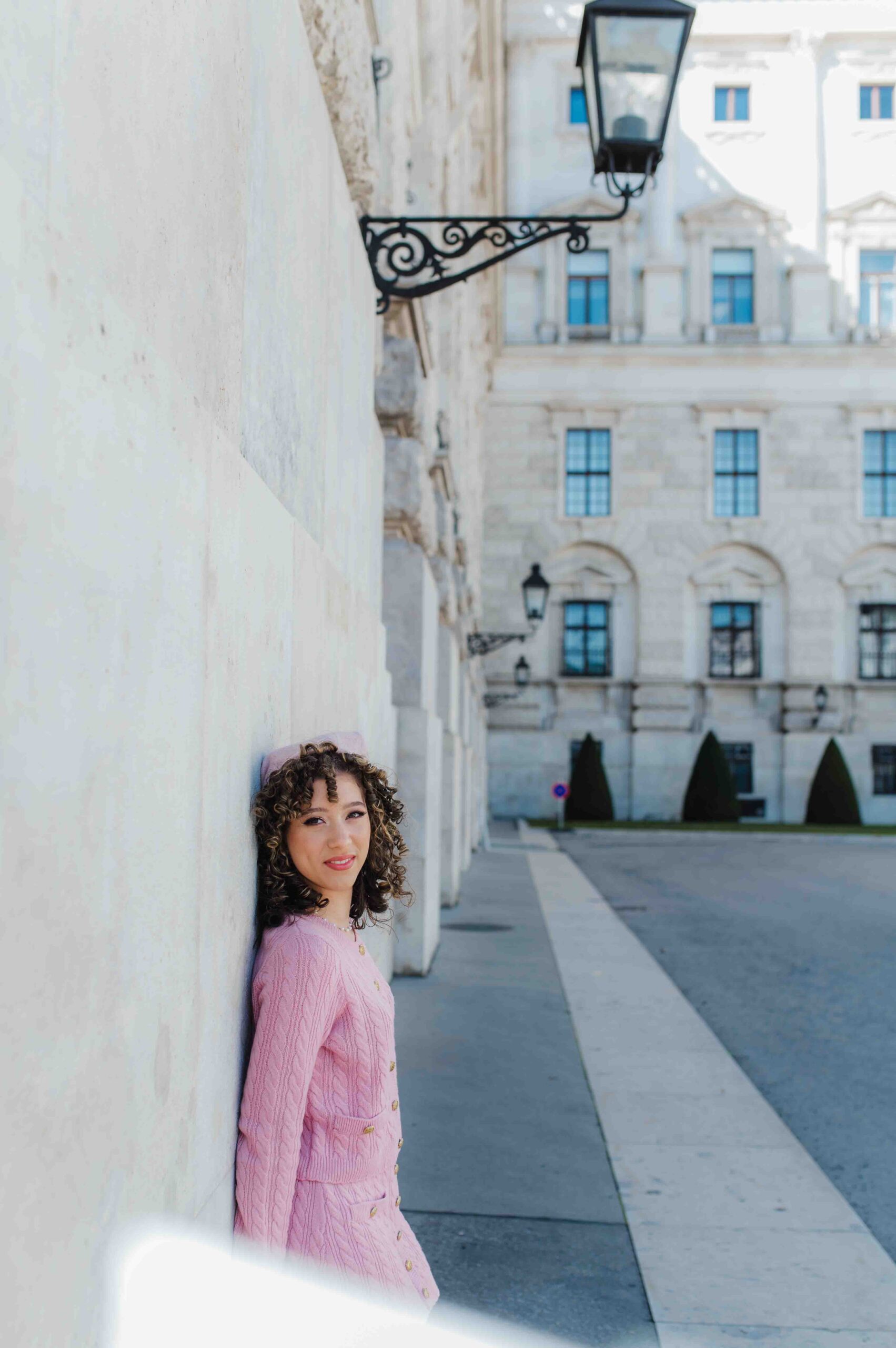 Teenage girl in pink dress leaning against a wall during portrait photo shoot in Vienna