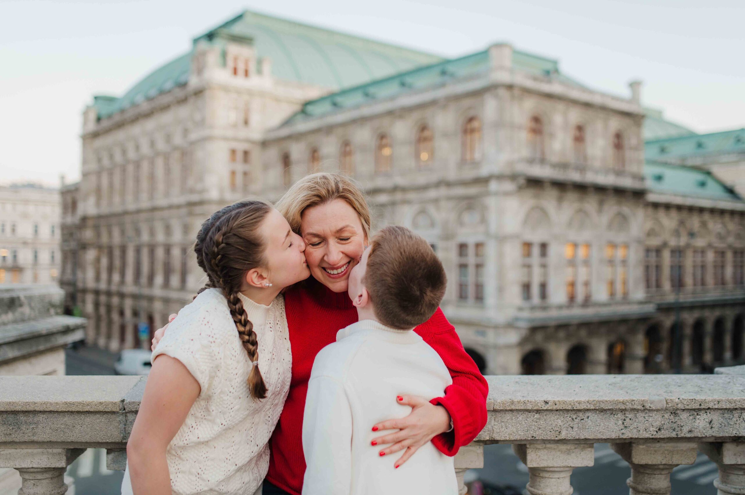Mother hugging her two children during family photo shoot in Vienna city center