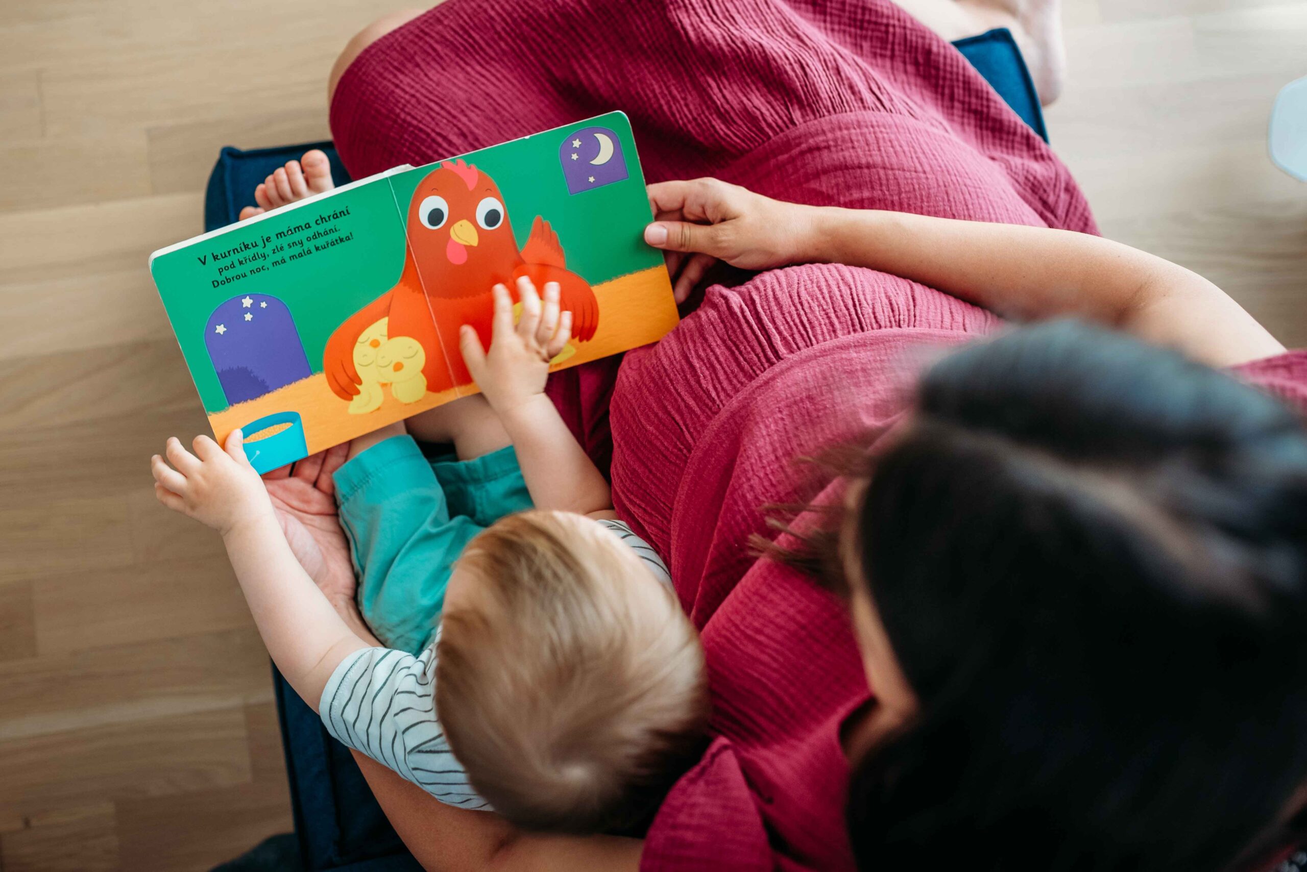 Pregnant mother reading a picture book with her toddler during an at-home maternity photo shoot