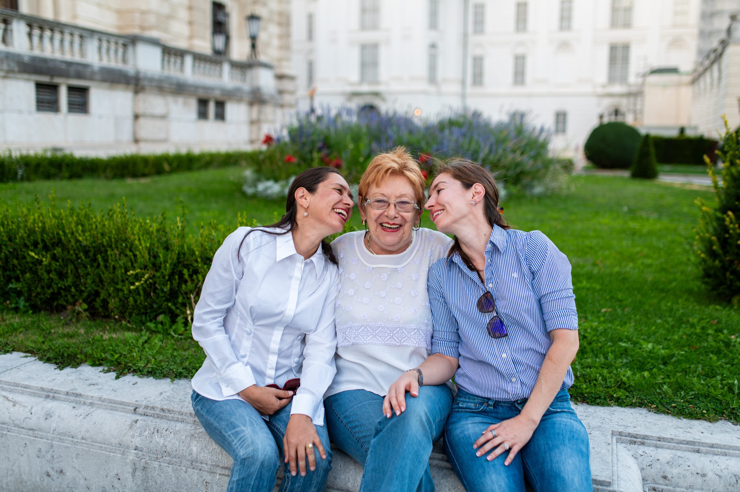 Mother sitting between her two adult daughters as they laugh together during a family photo shoot in Vienna.