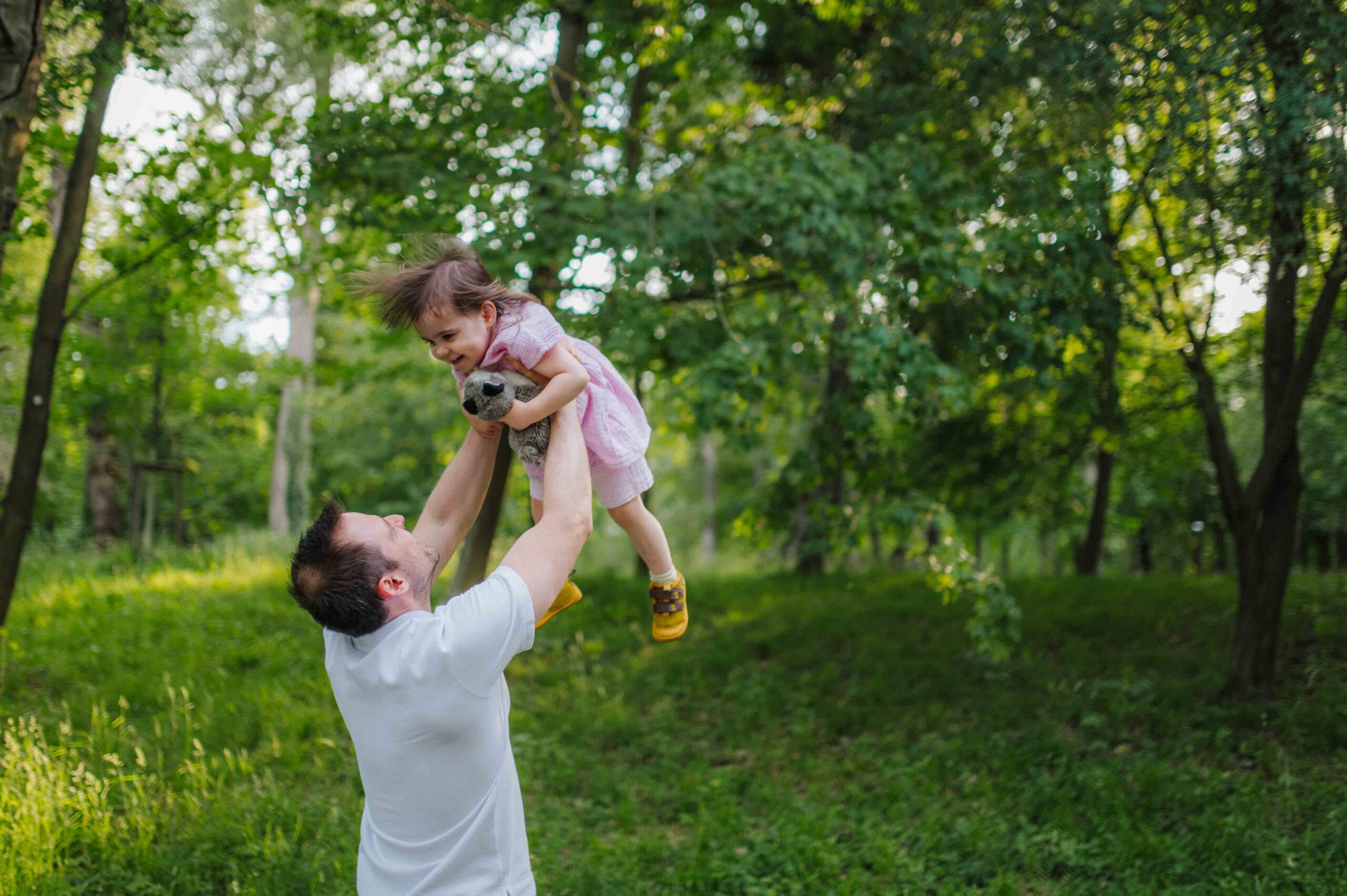 Father lifting his young daughter into the air during a playful family photo shoot in Vienna