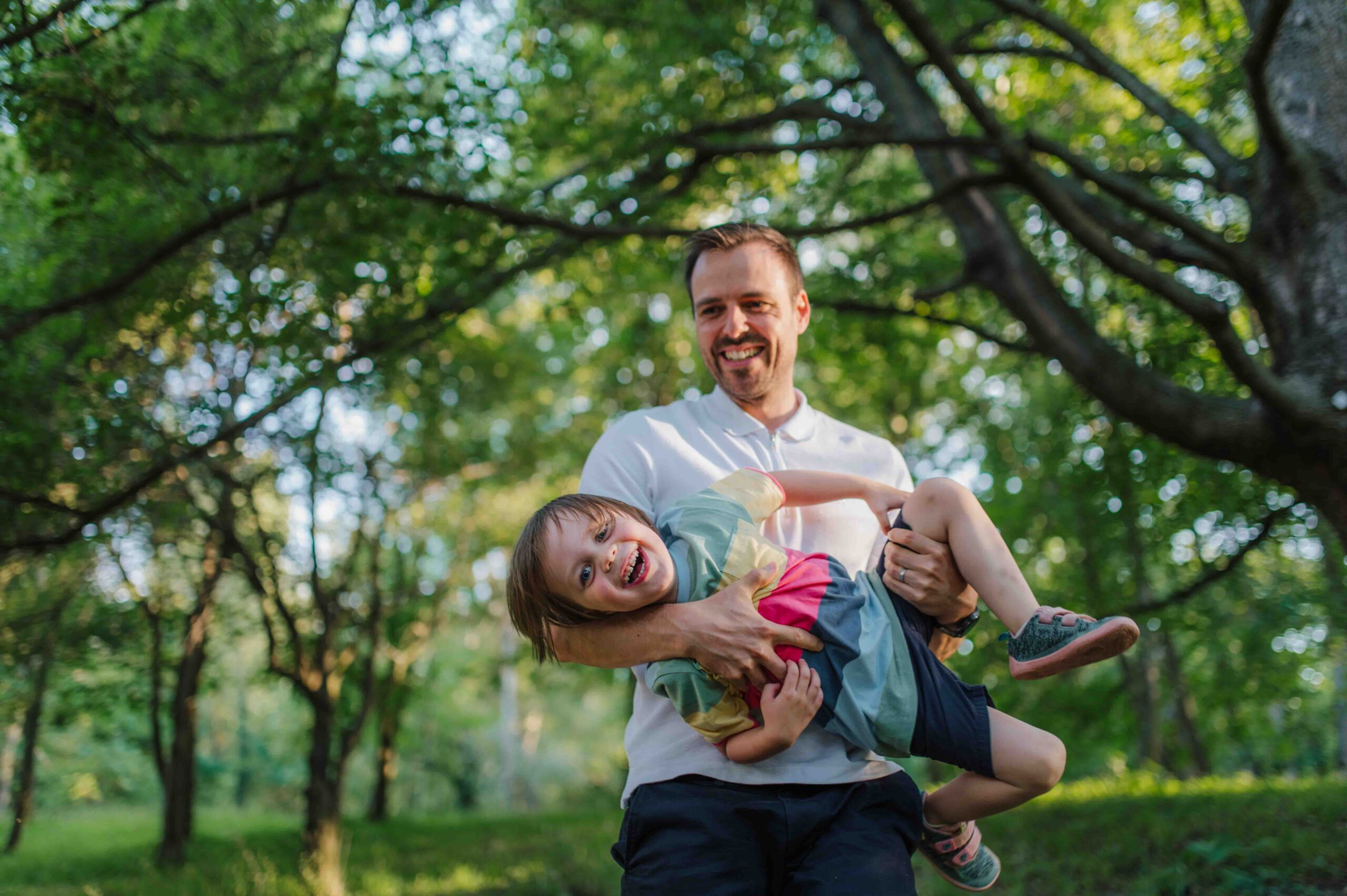 Father and young child laughing and playing together during a family photo shoot in Vienna